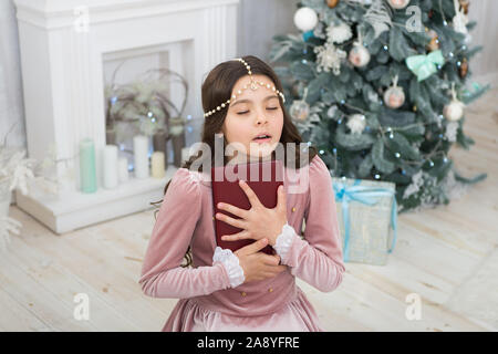 Se sentir reconnaissant. Esprit de Noël. Lecteur peu profiter de la lecture à la maison. Meilleur livre De Noël. Boutique Livres commerciaux. Peu de sourire enfant lire livre. Nouvel an. Petite fille lecture histoire de Noël. Banque D'Images