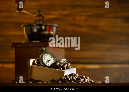 Grain de café et montre de poche. Meuleuse manuelle sur table en matinée. Concept de café. Banque D'Images