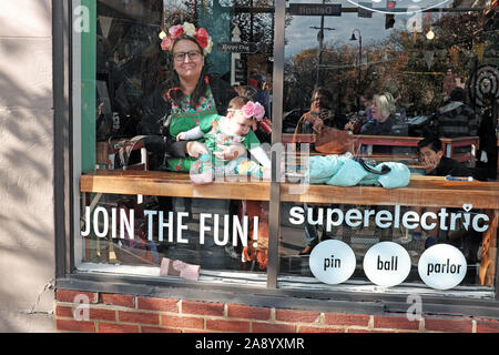 Femme tient son bébé dans la fenêtre du Parlor Superelectric Pinball dans le Gordon Square Arts District de Cleveland, Ohio, États-Unis. Banque D'Images