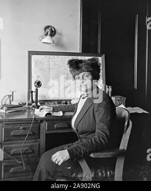 Woman sitting at desk with old telephone ca. 1910-1920