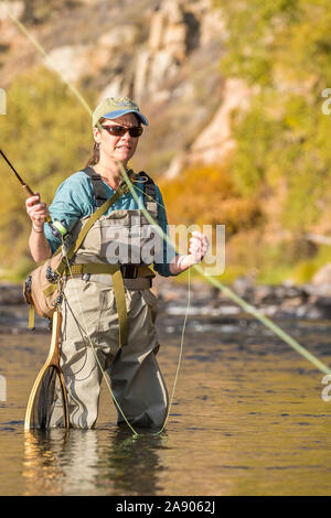 Une femme jette sa canne et moulinet de pêche sous le soleil d'après-midi d'automne dans le nord du Colorado. Banque D'Images