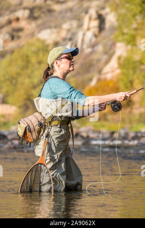 Une femme jette sa canne et moulinet de pêche sous le soleil d'après-midi d'automne dans le nord du Colorado. Banque D'Images