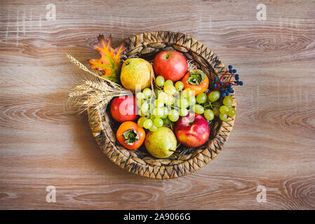 Vue de dessus de divers fruits d'automne colorés dans un panier en osier sur la table en bois. Banque D'Images