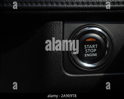 Moteur Start-Stop Touche avec voyant orange sur fond noir console voiture avec copie espace. Banque D'Images