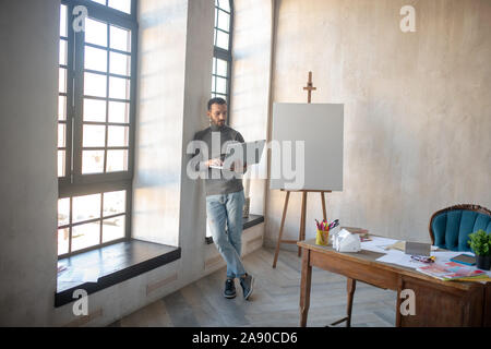 Le designer d'intérieur holding laptop tout en se tenant près de window Banque D'Images