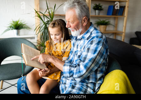 Grand-père barbu et son petit-fils ont du plaisir de lire un livre ensemble Banque D'Images