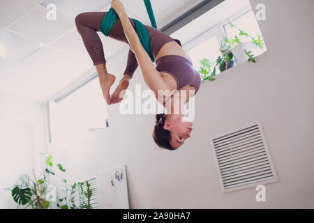 Yoga anti-gravité aérienne concept. Woman practicing yoga in fly studio de yoga anti-gravité à l'aide de green hamac. Banque D'Images