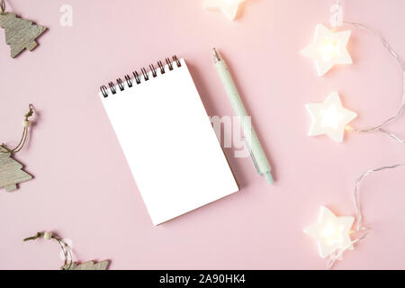 Ordinateur portable blanc feuille sur fond rose avec guirlande Banque D'Images