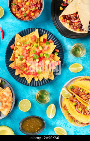 La nourriture mexicaine, de nombreux plats de la cuisine du Mexique, télévision lay, top shot sur un fond bleu. Nachos, tequila, coquilles à tacos, burritos, chili con carne Banque D'Images