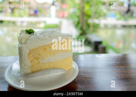 Gâteau blanc de noix de coco et crème. Gâteau maison à texture douce sur la table dans un jardin avec espace copie l'après-midi. Banque D'Images