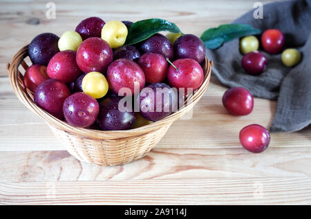 Les prunes mûres dans un grand panier en osier. Banque D'Images