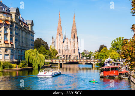 Vue avant de l'église Saint-Paul de sur les rives de l'Ill à Strasbourg, en France, avec un kayakiste et un bateau de croisière. Banque D'Images