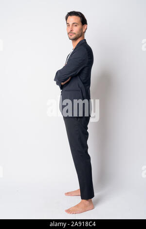 Full body shot profile view of Hispanic businessman looking at camera with arms crossed Banque D'Images