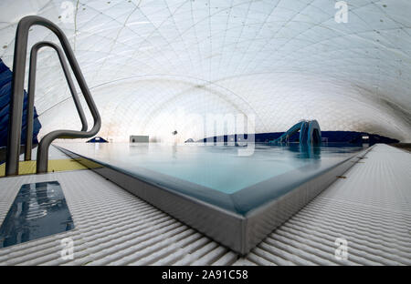 Berlin, Allemagne. 12 Nov, 2019. Le nouveau dôme d'air et d'un toboggan dans la piscine à Wedding combiné Seestraße se reflètent dans l'une des deux piscines de 50 mètres dans la piscine extérieure. La cérémonie de mise à l'Allemagne de dôme d'air d'une surface de 60 x 68 mètres a eu lieu aujourd'hui. Le couplage des deux piscines en plein air va ajouter 2072 mètres carrés d'eau pour les mois d'hiver. Crédit : Bernd von Jutrczenka/dpa/Alamy Live News Banque D'Images