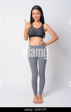 Full body shot of young Asian woman giving Thumbs up Ready pour salle de sport Banque D'Images