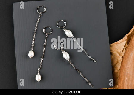 Boucles d'argent sur une chaîne. Close-up. Disposés sur un support en bois. Vue de dessus. Le concept de bijoux et de joaillerie. Cadeaux pour les femmes. shopping Banque D'Images