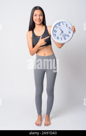 Full body shot of young Asian woman montrant l'heure et prêt pour salle de sport Banque D'Images