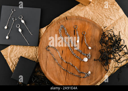 Boucles d'argent sur une chaîne. Close-up. Disposés sur un support en bois. Vue de dessus. Le concept de bijoux et de joaillerie. Cadeaux pour les femmes. shopping Banque D'Images