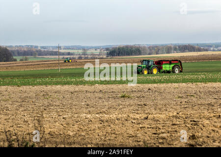 Tracteur à roues avec une remorque pour l'épandage de fumier. Le deuxième tracteur laboure la terre. Les travaux d'automne dans une ferme laitière. Podlasie, Pologne. Banque D'Images