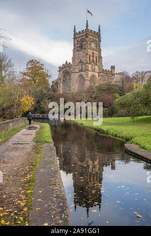 Kidderminster, UK. 12 novembre, 2019. Météo France : après un autre démarrage humide et froid dans le Worcestershire, le soleil d'automne fait une apparition bienvenue. Eglise St Mary (l'église paroissiale de Kidderminster) se dresse majestueusement le long du pittoresque canal - sa tour tout juste visible à travers les feuilles mortes qui flottent à la surface de l'abîme de l'eau du canal. La vue arrière d'un piéton est capturé, en prenant une marche d'automne le long d'un chemin de halage du canal du Royaume-Uni. Credit : Hudson Lee Banque D'Images