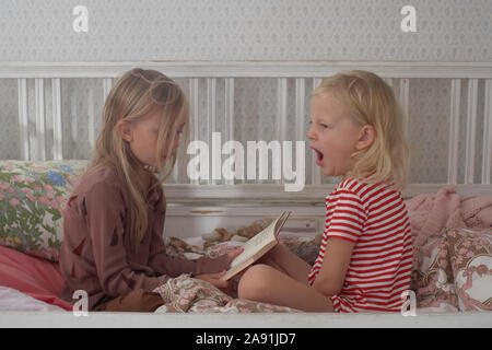 Sisters sitting on bed Banque D'Images