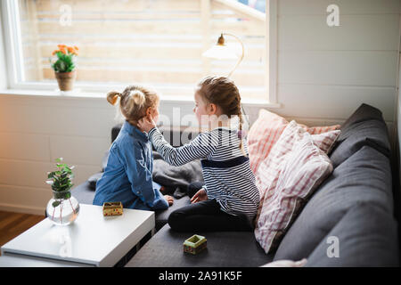 Sisters sitting on sofa Banque D'Images