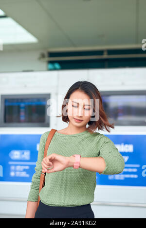 Belle asiatique femme regarde montre-bracelet pour contrôler le temps. Banque D'Images