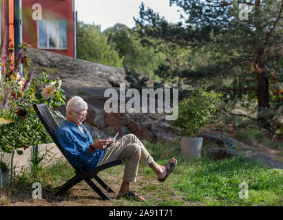 Man in garden reading newspaper Banque D'Images