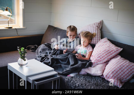 Sisters sitting on sofa Banque D'Images