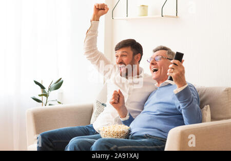 Personnes âgées et les personnes d'âge mûr Père Fils regarder du sport à la télévision Piscine Banque D'Images