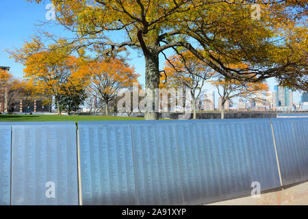 NEW YORK, NY - 04 NOV 2019 : le mur d'honneur d'immigrants américains à Ellis Island, avec des arbres d'automne, coloré. Banque D'Images