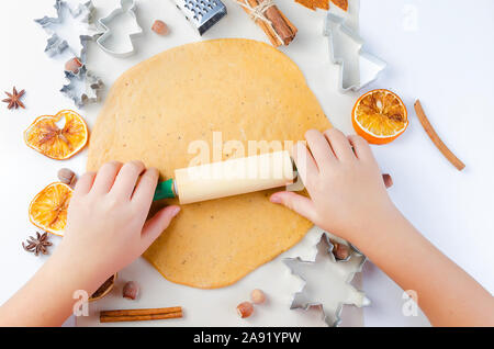 Mains d'un enfant avec un rouleau sur une pâte pour noël gingerbread cookies, la cuisson, l'arrière-plan d'événements concept vacances hiver Banque D'Images