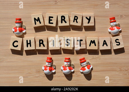 Joyeux Noël en 3D wooden alphabet lettres avec Santa bonhommes de décorations sur un fond de bois de bambou Banque D'Images