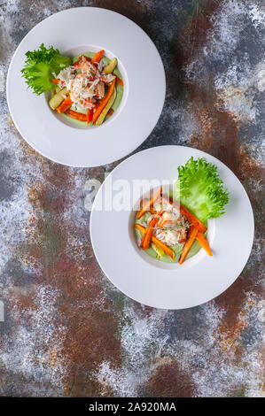 Avec salade de chair de crabe des neiges, d'avocat et de légumes. Deux portions sur un fond rouillé. Shot verticale Banque D'Images