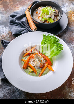 Close-up avec salade de chair de crabe des neiges, la soupe avec de la viande du crabe des neiges, les nouilles Udon et légumes. Servir sur une serviette gris et un fond rouillé. S verticale Banque D'Images