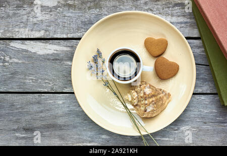 Petit-déjeuner scandinave à la mer : café, biscuits en forme de coeur, lavande, Shell et des livres sur la vieille table en bois patiné, profiter de moments simples de votre Banque D'Images