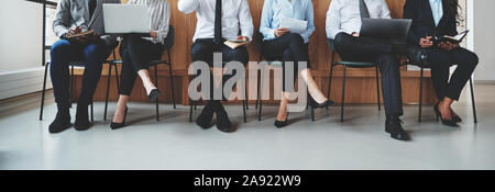 Groupe d'affaires diversifié méconnaissables assis dans des chaises dans un bureau d'attente de réception d'être interviewés Banque D'Images