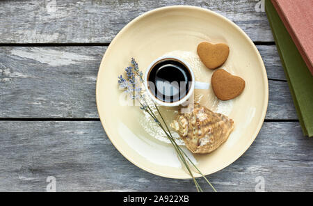 Petit-déjeuner scandinave à la mer : café, biscuits en forme de coeur, lavande, Shell et des livres sur la vieille table en bois patiné, profiter de moments simples de votre Banque D'Images