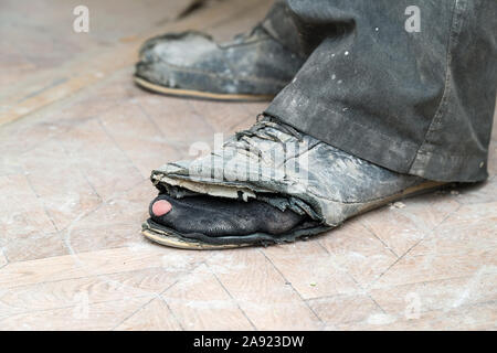 Vieilles bottes déchirées sur les pieds de l'homme. Bottes avec des trous. Selective focus Banque D'Images