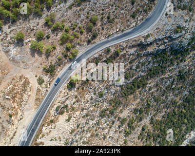 Deux voitures rouler sur une route de montagne sinueuse. Vue aérienne du haut vers le bas. Banque D'Images