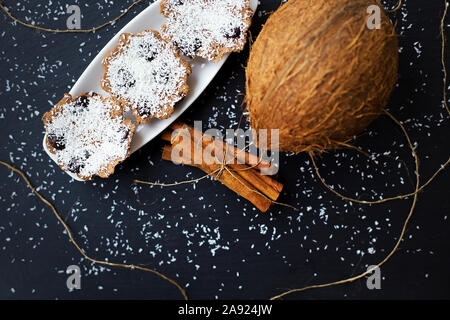 Muffins à la noix de coco avec le chocolat et cannelle sur un fond noir et de noix de coco entière Banque D'Images