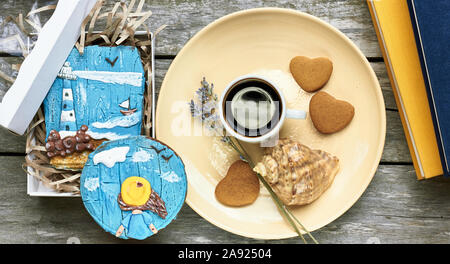 Petit-déjeuner scandinave à la mer : café, biscuits en forme de coeur, lavande, Shell et des livres sur la vieille table en bois patiné, profiter de moments simples de votre Banque D'Images