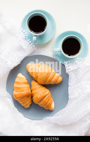 Deux tasses de café avec les croissants sur l'arrière-plan de lacets Banque D'Images