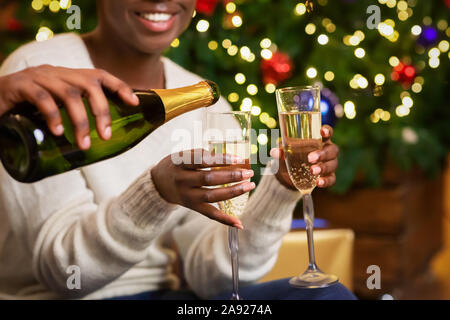 Cheerful black couple drinking champagne près de l'arbre de Noël à la maison Banque D'Images