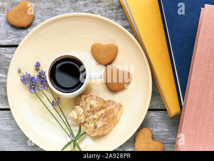 Vacances scandinaves petit-déjeuner à la mer : café, biscuits en forme de coeur, lavande, Shell et des livres sur la vieille table en bois patiné, y profiter d'un moment Banque D'Images