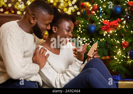 Happy black woman reading carte de Noël souhaits de son mari Banque D'Images