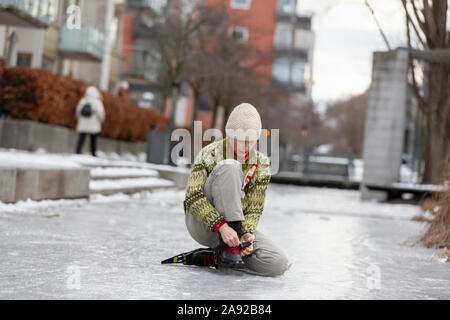 Woman putting sur patins à glace Banque D'Images