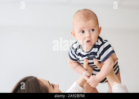 Portrait of cute infant baby levé dans l'air par maman Banque D'Images