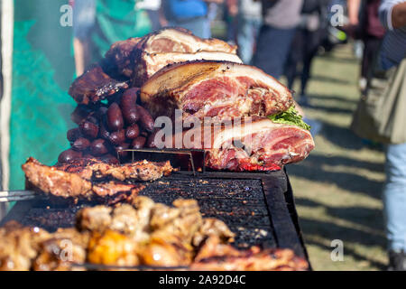 Une pile de fumé et grillé viande et charcuterie. Des morceaux de porc grillés sont à un blocage de l'alimentation. Festival de l'alimentation, journée d'été, en zone de foule floue Banque D'Images