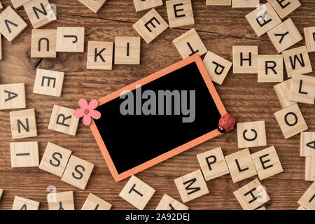 Un tableau vide et alphabets cube sur une surface en bois Banque D'Images